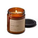 The PNW Vibe candle burns in its amber jar with white wax.